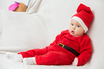 Wall Mural - Seven months old baby girl in Santa Claus dress sitting sideways