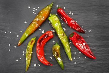 Wall Mural - Grilled peppers with salt on dark table, top view