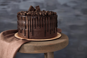 Wall Mural - Tasty chocolate cake on chair on dark background