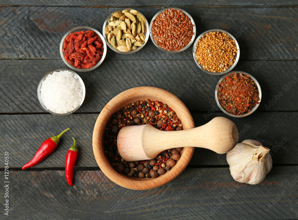 Composition with different spices and mortar on dark wooden background