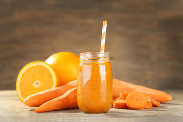 Jar with carrot and orange smoothie on wooden table