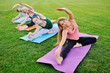 group of people doing yoga on the green with fresh grass outdoors. Healthy lifestyle