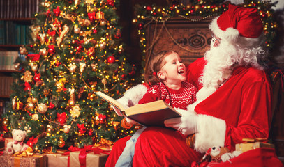 Wall Mural - happy child girl with Santa reading book