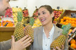 smiling woman choosing different fruits at farm food store display
