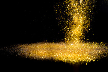 Sprinkle gold dust on a black background with copy space.