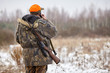 Hunter in camouflage clothes with hunting rifle and mobile phone during a winter hunting