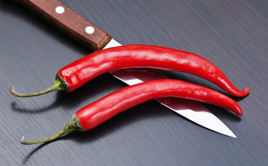  red chili peppers and knife on the kitchen table