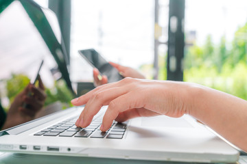 Wall Mural - Closeup of business woman hand typing on laptop keyboard with mo