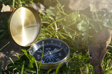 closeup of magnetic golden compass in the grass showing right directions
