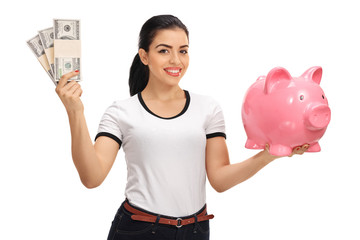 Wall Mural - Young woman holding bundles of money and piggybank