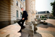 © IVASHstudio - young and handsome groom in black suit standing near manor