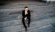 © IVASHstudio - young and handsome groom in black suit sitting on the stairs