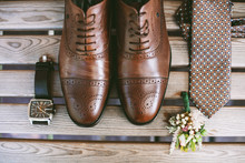 Accessories Of A Groom: Shoes, Boutonniere, Tie And Clock On A Wooden Surface