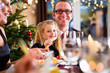 Eltern und Kinder beim Anstoßen mit Wein und Wasser am Heiligabend Weihnachtsessen