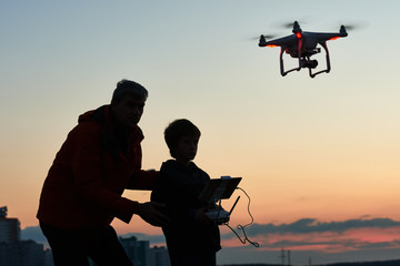 Wall Mural - man operating of flying drone at sunset