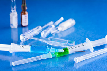 Medical vials for injection with a syringe isolated on blue background.