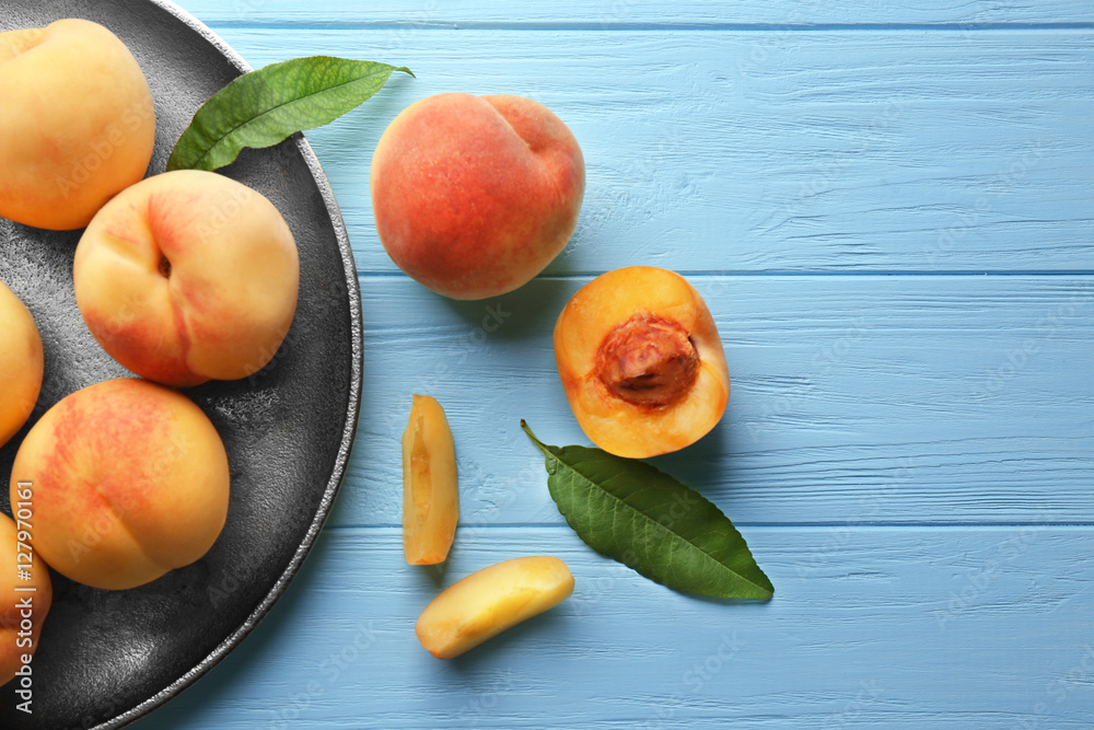 Juicy peaches in silver tray on turquoise wooden background