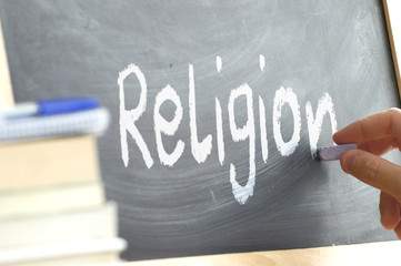 A person writing in a blackboard during Religion class in a school. Next, some books.