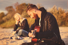 Man Playing Guitar For Girl On Beach