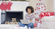 © Dash - Young woman doing Christmas shopping online sitting on the floor in front of the tree with her laptop and credit card looking at merchandise on offer with a thoughtful expression.