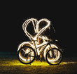 Silhouette of mountain bicycle on Green meadow with Beautiful Fireworks sparkler heart symbol at night