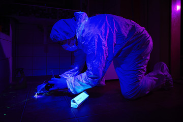 Criminologist collects DNA under UV light from blood stains