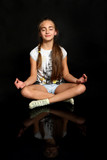 Fototapeta  - Śliczna dziewczynka medytuje, ćwiczy jogę, na czarnym tle.