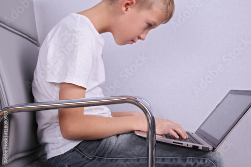 Fotografía Children bad incorrect sitting posture. Boy using laptop computer