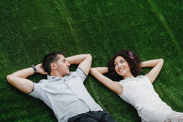 Wall Mural - Young cute mixed race Couple Lying on Grass. Engagement Outdoor Shot