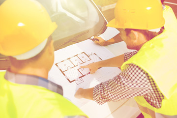 Canvas Print - close up of builders with blueprint on car hood