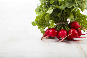 Ripe red radish with leaves on a wooden table close-up. Fresh ve