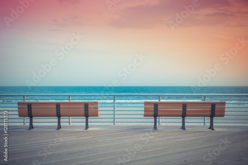 Fotografía pastel toned beach boardwalk benches with ocean and sunset