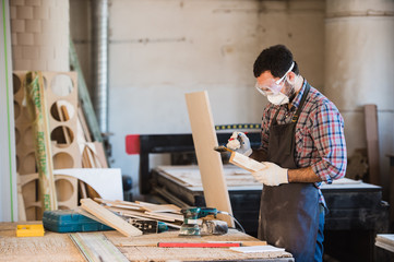 Horizontal view of professionally dressed carpenter varnishing a board