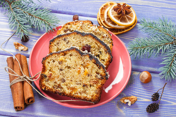 Fresh baked fruitcake for Christmas on plate and spruce branches on boards