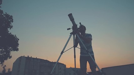 Wall Mural - man looking through a telescope.