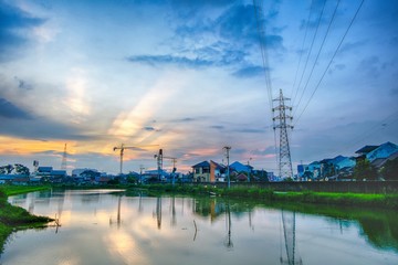 sunset in urban areas, featuring transmission towers, ponds that make beautiful reflection, crane, r