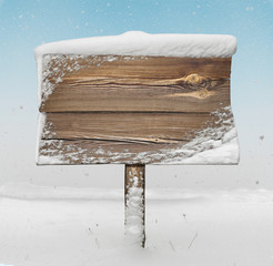 Wooden signpost with snow on it and snowfall