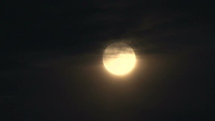 Wall Mural - full moon rising through clouds, glowing bright in night sky.