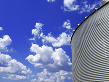Low Angle View Of Metal Grain Bin With Blue Sky In The Background 