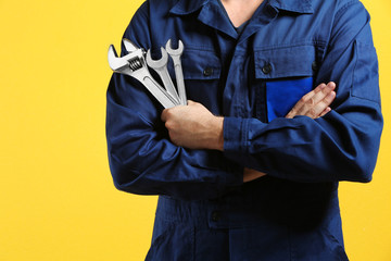 Wall Mural - Mechanic with crossed arms and wrench standing on yellow background