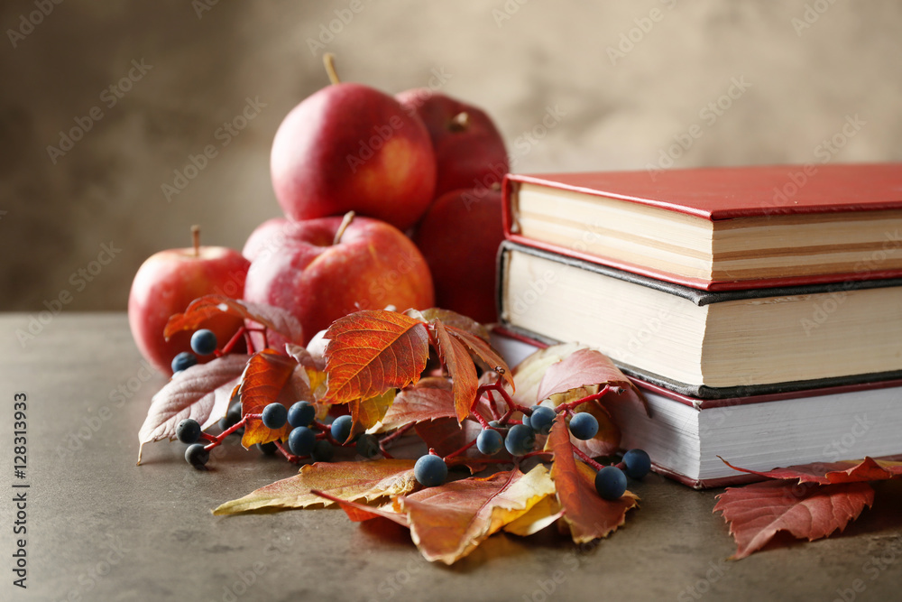 Beautiful autumn composition with pile of books on grey background