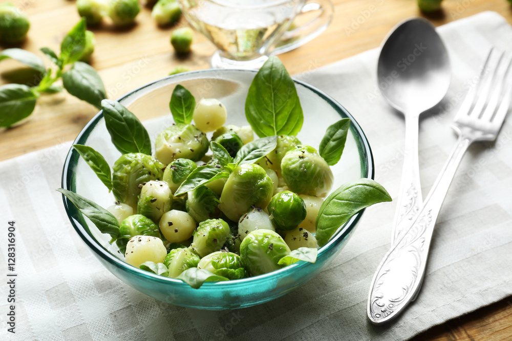 Bowl with delicious salad of Brussels sprouts and basil on table