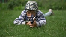 Child In Camoflauge Playing War Shoots A Toy Gun