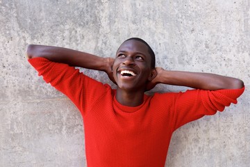 Wall Mural - Smiling black guy standing with hands behind head