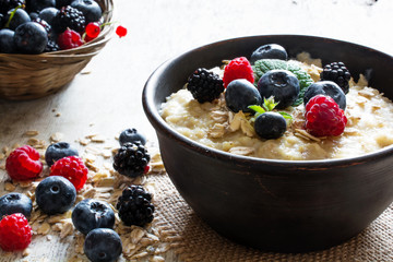 Wall Mural - oatmeal porridge in ceramic bowl with fresh ripe berries and mint