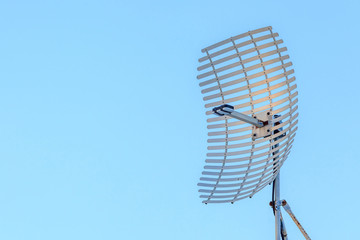 Microwave antenna dish on clear blue sky background.