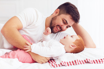 Wall Mural - happy father playing with adorable baby in bedroom