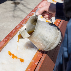 Wall Mural - Man pouring hot maple syrup on snow