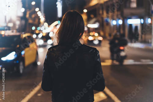 Fotografie, Obraz Hipster girl in black leather jacket from back on background illumination glow b