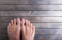 Male Feet On Wooden Background.